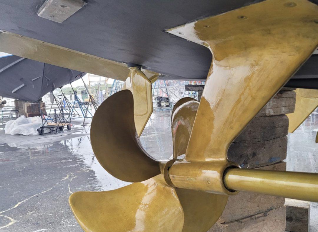 A close-up of a yellow propeller mounted on a boat, showcasing its vibrant color against the vessel's surface.