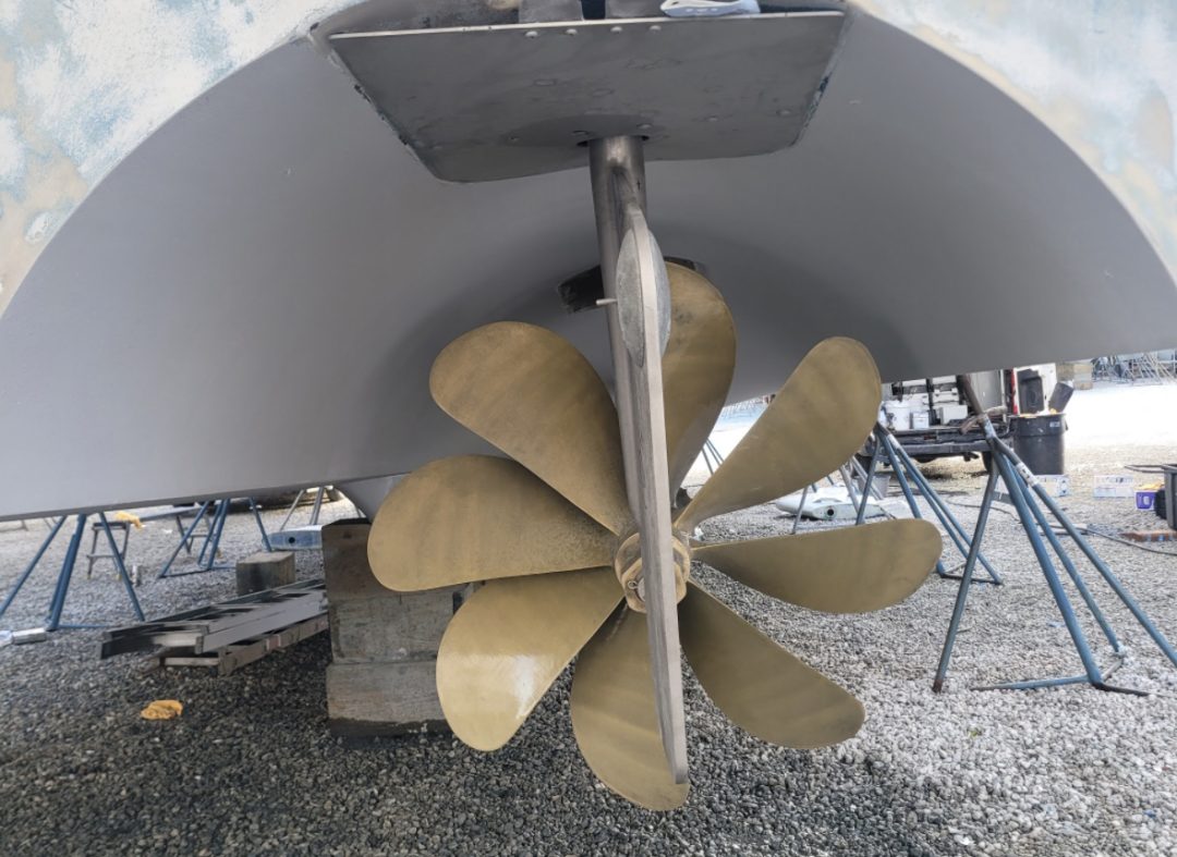 Close-up of a boat featuring a shiny propeller, highlighting its design and functionality in a marine setting.