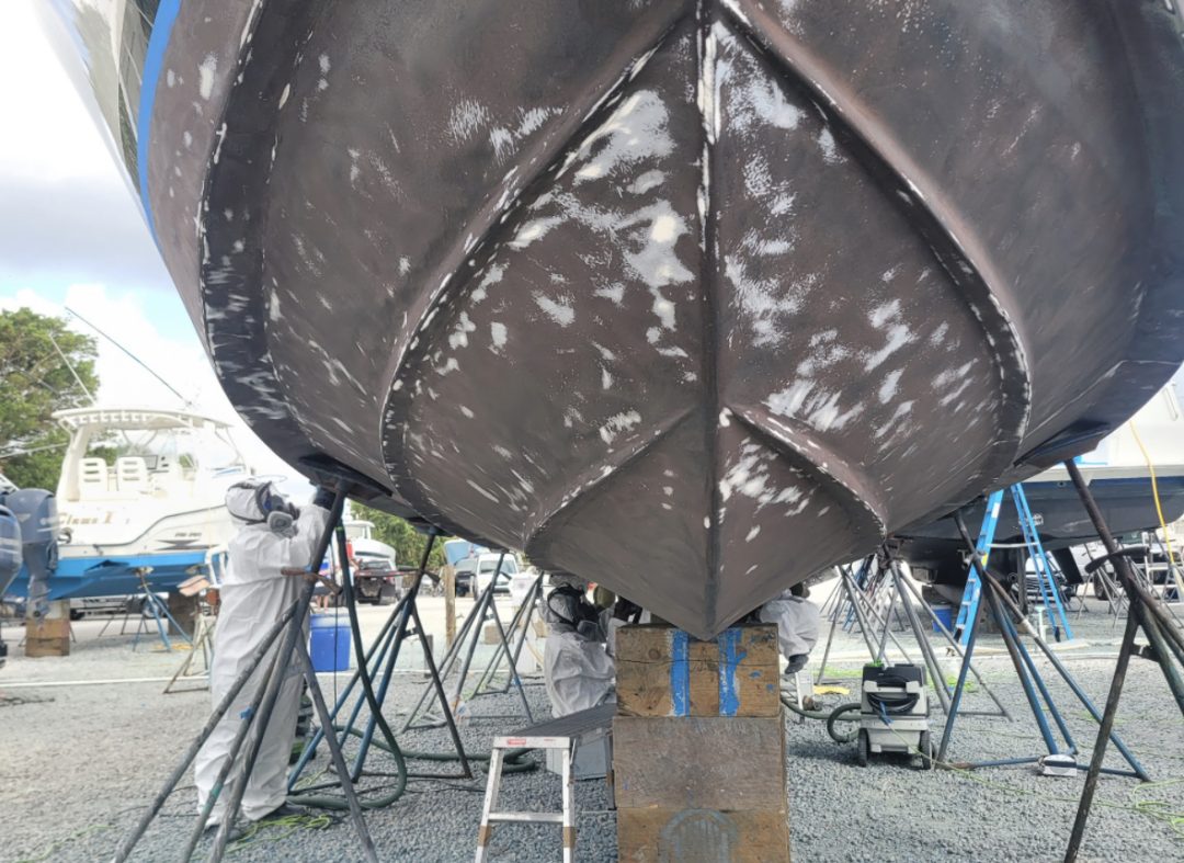 A boat is being painted with vibrant blue paint, showcasing the artistry of the painting process.